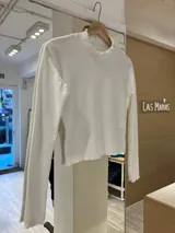 Remera blanca de morley de algodón, de manga larga con terminaciones fruncidas en cuello y mangas.