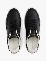 Zapatillas de corte bajo estilo tenis, confeccionadas en piel color negro. Presentan suela de goma blanca, detalle metalizado en el talón, ojal superior dorado y monograma TH metálico en el lateral.