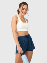 Top deportivo de soporte medio color blanco, con diseño de espalda con tirante central grueso y sujetador integrado con almohadillas removibles.