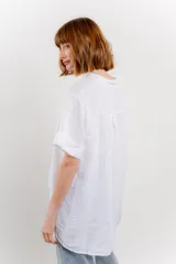 Blusa blanca de lino con escote en V abotonado y mangas cortas arremangadas.