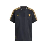 Camiseta de fútbol Adidas del Manchester United, modelo Terrace Icons. Diseño negro con finas rayas verticales en violeta, detalles dorados en las tres tiras de los hombros, logo de Adidas y escudo del club. Cuello redondo con ribete violeta y amarillo.