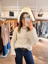 Sweater de punto canalé en color beige, con diseño de cuello bote, mangas largas amplias y corte crop. Presenta una textura acanalada vertical que recorre toda la prenda.