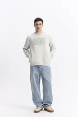 Buzo de algodón color marrón chocolate, con cuello redondo, mangas largas y estampa frontal con el nombre de la marca repetido en tono sobre tono.