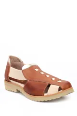 Zapato tipo sandalia plana de cuero liso en color rojo cereza con detalles en color crema. Presenta paneles laterales elásticos, suela dentada y diseño con aberturas.