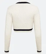 Suéter cropped de punto texturizado color crema, con escote en V y detalles a contraste en negro en mangas, cuello y busto.