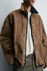 Sobrecamisa de corte boxy fit confeccionada en tejido de algodón con estructura diagonal y efecto lavado. Presenta cuello solapa, cierre frontal con botones a presión, mangas largas con puños ajustables y bolsillos frontales de plastrón.