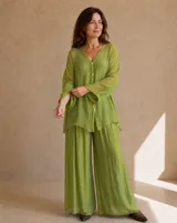 Camisa holgada de seda en color verde lima, con cuello en V, mangas largas amplias y cierre frontal de botones claros.