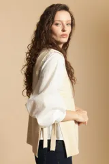 Chaleco de tejido de punto en color crema, con cuello alto y diseño acanalado. Presenta una silueta relajada con aberturas laterales.