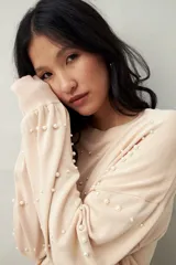 Sweater de punto color beige claro, con cuello redondo y manga larga, decorado con perlas aplicadas en patrón de rombos.