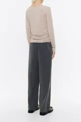 Pantalón negro de corte ancho y tiro alto, con cintura elástica fruncida y pliegues frontales.