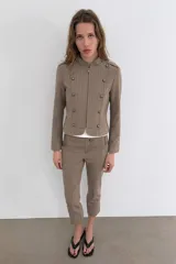 Pantalón capri de tiro medio con raya diplomática en tonos beige y marrón. Presenta trabillas, bolsillos laterales y cierre frontal con cremallera y botón metálico.