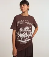 Remera de algodón color marrón, con cuello redondo, mangas cortas y estampado western de caballos con la frase 'Wild Heart' en color blanco.