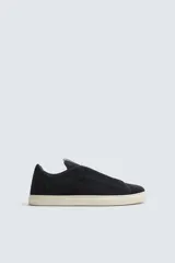 Zapatilla urbana de hombre confeccionada en piel con acabado de serraje, diseño minimalista con cordonera oculta y suela de goma a contraste.