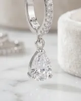 Aros de plata 925 con diseño de argolla pequeña decorada con circonias y dije colgante en forma de gota.