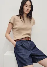 Short denim de tiro medio en color azul oscuro, con diseño recto, pinzas delanteras, bolsillos laterales y traseros, y cierre frontal con cremallera y botón.
