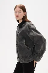 Campera de jean con lavado gris desgastado, cuello camisero en pana negra, cierre frontal con botones y bolsillos laterales amplios.