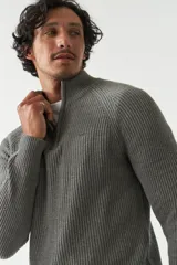 Sweater gris de punto con cuello alto y medio cierre con cremallera.