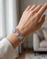Pulsera de cadena de acero con eslabones tipo bolita y tres dijes colgantes en forma de corazón con esmalte en colores pastel: rosado, blanco y turquesa.