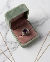 Anillo de plata 925 con piedra amatista central de corte circular, rodeada por un diseño de pequeñas esferas metálicas.