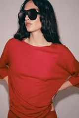 Remera oversize de punto rojo, con cuello redondo y mangas de largo medio por debajo del codo, diseño holgado y amplio.