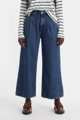 Pantalón de jean azul oscuro, corte ancho, tiro medio y bolsillos laterales.