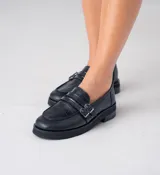 Mocasín de cuero vacuno negro con detalle de pieza de cuero con textura de cocodrilo y hebillas metálicas. Suela de caucho con plataforma.