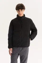 Campera puffer negra con cuello alto y cierre frontal con cremallera.