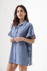 Camisa azul de corte holgado, con cuello clásico, cierre frontal con botones, mangas cortas con volados y largo hasta la mitad del muslo.