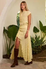 Conjunto de dos piezas en color amarillo, compuesto por un top sin mangas con textura plisada y una falda midi con frunce lateral ajustable que permite regular la abertura frontal.