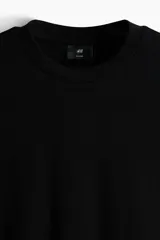 Remera de corte holgado en punto interlock de algodón, con cuello redondo acanalado, hombros caídos y bajo recto.