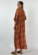 Vestido largo de viscosa con estampado de rayas verticales en tonos marrones y beige, con cuello en V y mangas cortas.