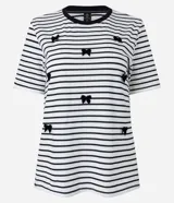 Blusa de media malla a rayas horizontales blancas y negras, con cuello redondo y mangas cortas. Aplicación de moñas negras.
