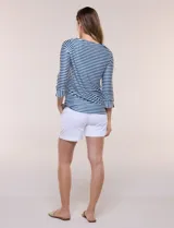 Remera de agua de silueta estilizada confeccionada en tejido técnico elastizado con protección solar UPF 50, con escote barco amplio y mangas 3/4 terminadas con puño en rayas verticales a contraste con pequeña abertura. Presenta aberturas laterales en el bajo decoradas con botones dorados grabados y ruedo recto de calce cómodo.
