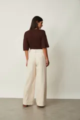 Jean azul oscuro de corte wide leg y tiro alto, con costuras pespunteadas verticales al frente y cinturón incorporado con hebilla cuadrada.