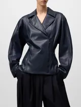 Chaqueta tipo biker de cuero sintético en color azul oscuro, con solapas, cierre frontal cruzado con cremallera, cintura entallada y mangas largas. Cuenta con bolsillos delanteros con cremallera invisible.