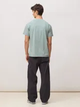 Camiseta de algodón orgánico con efecto lavado, cuello redondo, manga corta y bolsillo frontal en el pecho con etiqueta tejida con logo.