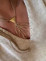 Collar dorado con dije triangular y colgantes en forma de ramas.