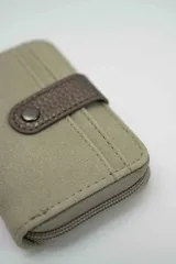 Billetera compacta de gamuza color beige con detalle de solapa central en cuero sintético marrón oscuro y cierre perimetral.