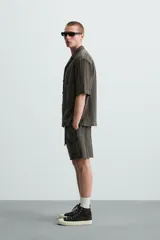 Bermuda de algodón color blanco, de corte relajado (relaxed fit), con cintura elástica ajustable mediante cordón. Posee bolsillos laterales y un bolsillo trasero de plastrón. Presenta un bordado en contraste en la pernera.