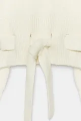Jersey de punto con escote barco y manga larga. Presenta un diseño corto con detalle de cinturón integrado en el mismo tejido y bolsillos decorativos en la parte frontal.