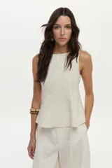 Top de lino color beige con cuello bote y diseño con peplum, sin mangas y con cierre invisible en la espalda.