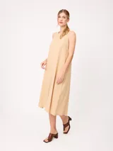 Vestido midi sin mangas de corte recto y holgado, color beige, con cuello redondo y bolsillos laterales.
