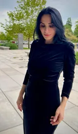 Vestido midi de terciopelo negro, con mangas largas, cuello redondo y detalle de encaje bordado en el lateral de la cintura.