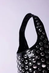 Cartera tipo hobo de PU acharolada color negro, cubierta de tachas plateadas.