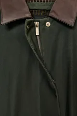 Trench oversize de color verde oscuro, con cuello de piel en tono marrón a contraste. Presenta manga larga con trabillas en los puños, bolsillos delanteros, cierre frontal con cremallera y botones ocultos bajo solapa, y abertura en la espalda.