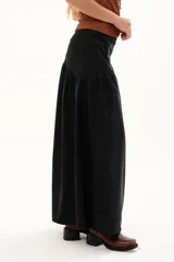 Pollera larga de color negro con corte a la cadera y detalle de frunce que aporta volumen y movimiento a la prenda. Confeccionada en tela suave con acabado tipo piel de durazno.