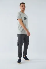 Pantalón cargo color beige, corte slim, con bolsillos laterales con botón, cierre con botón y puños en los tobillos.