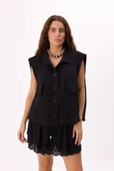 Chaleco negro sin mangas, estilo cargo con lavado suave, bolsillos frontales y botones negros.