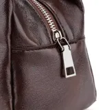 Bolso de hombro pequeño color marrón oscuro con acabado brillante, estilo baguette. Las asas son ajustables y están decoradas con ojales metálicos plateados.