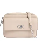 Cartera cruzada rectangular de piel sintética color beige claro, con solapa frontal y cierre de cremallera superior. Presenta un monograma metálico grande con las iniciales CK en tono plateado sobre la solapa. Incluye correa ajustable de cuero sintético y cadena metálica plateada.